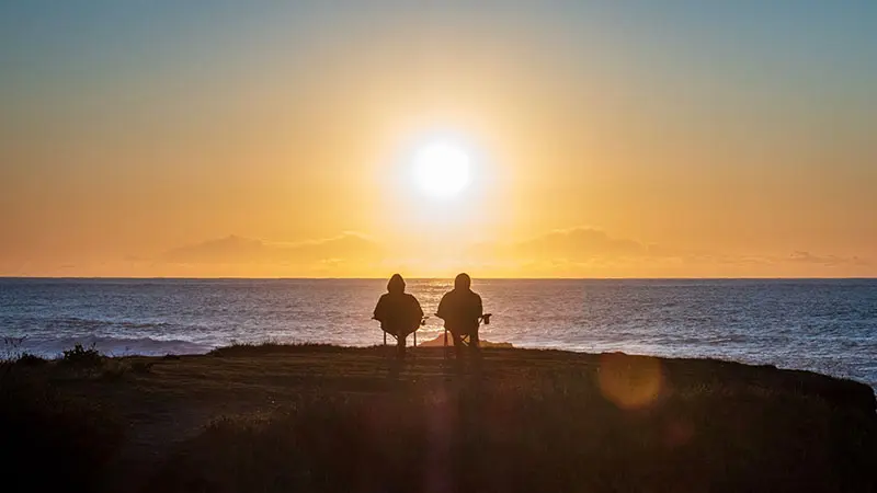 A couple with a comfortable retirement sitting together at the beach