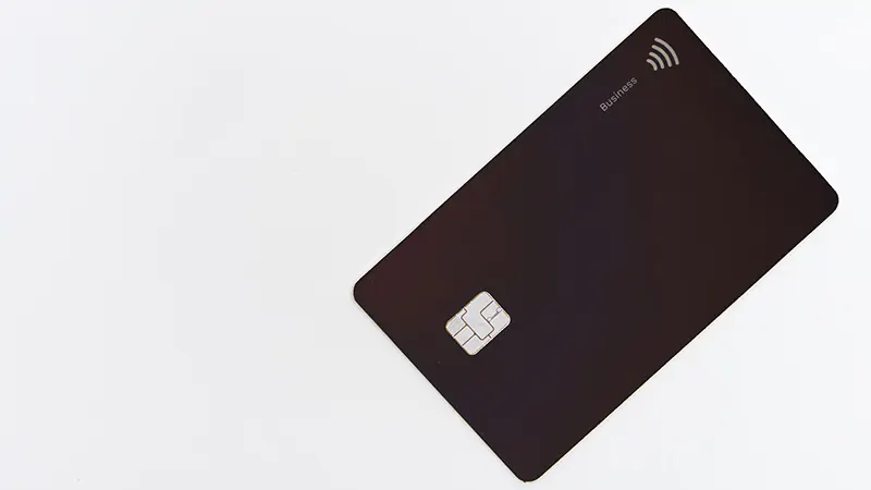 A black credit card featuring a payment chip and contactless payment